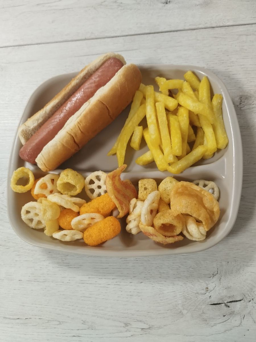 Menú infantil de perrito caliente con patatas fritas y snacks variados